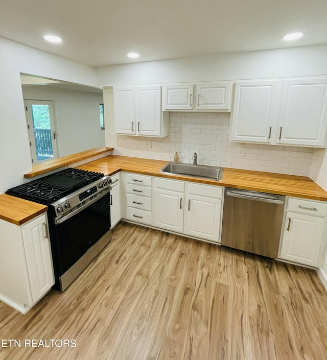 kitchen with butcher block countertops, white cabinetry, sink, and appliances with stainless steel finishes