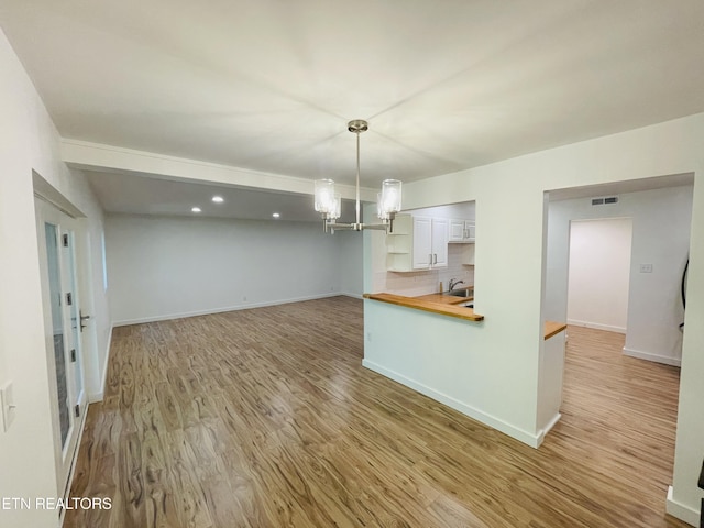 kitchen featuring wood counters, sink, decorative light fixtures, hardwood / wood-style flooring, and an inviting chandelier