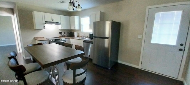 kitchen with stainless steel appliances, sink, decorative light fixtures, an inviting chandelier, and white cabinets