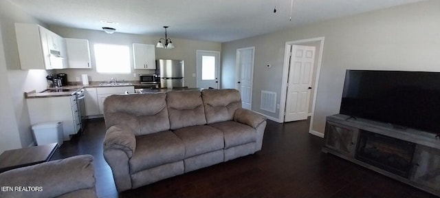 living room with sink, dark hardwood / wood-style floors, and an inviting chandelier