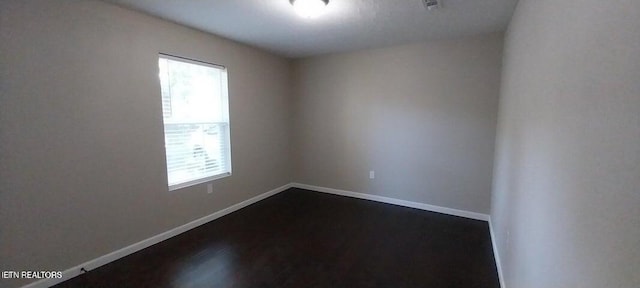 spare room with dark hardwood / wood-style flooring and a healthy amount of sunlight