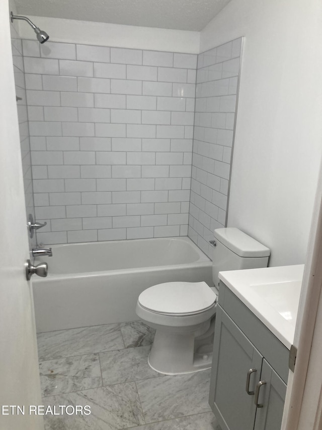 full bathroom featuring tiled shower / bath, vanity, a textured ceiling, and toilet