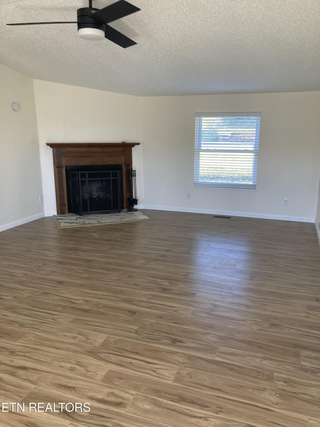 unfurnished living room with a textured ceiling, dark hardwood / wood-style floors, and ceiling fan