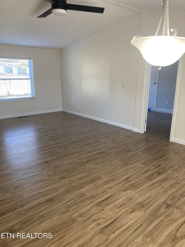 spare room featuring a textured ceiling, ceiling fan, and dark wood-type flooring