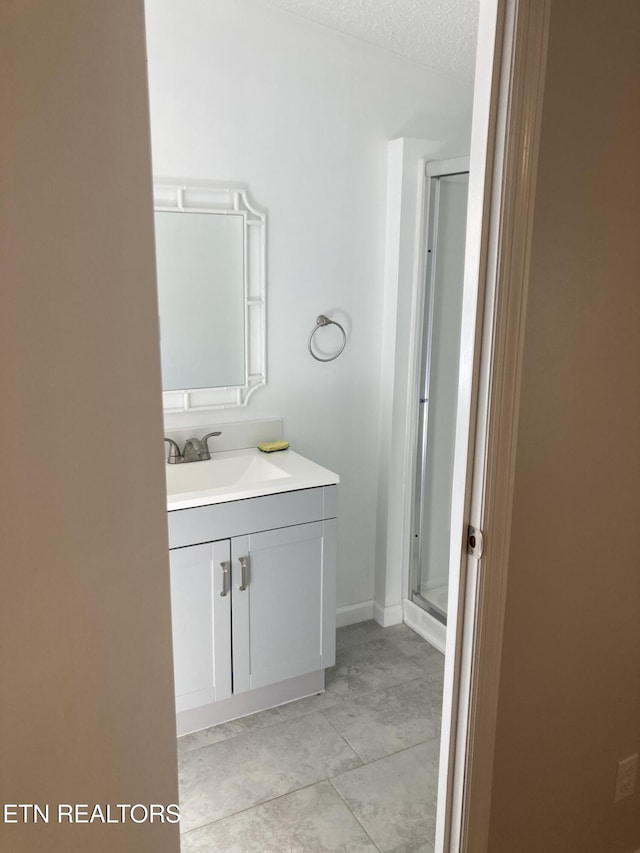 bathroom with tile patterned floors, vanity, a textured ceiling, and walk in shower