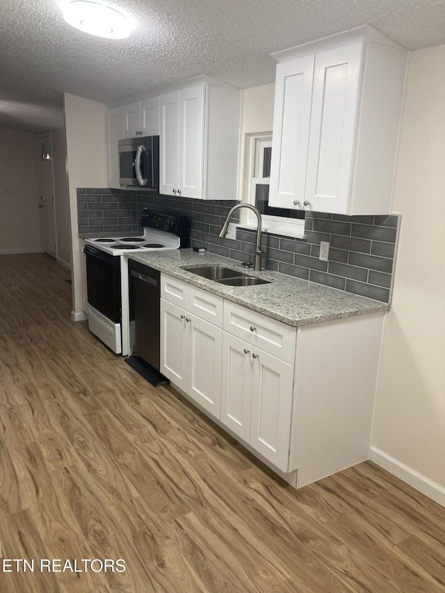 kitchen featuring black dishwasher, sink, white cabinets, and light wood-type flooring