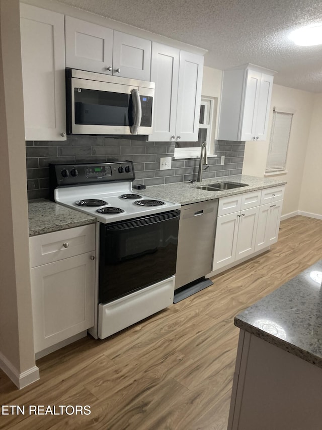 kitchen featuring white cabinets, sink, appliances with stainless steel finishes, tasteful backsplash, and light hardwood / wood-style floors