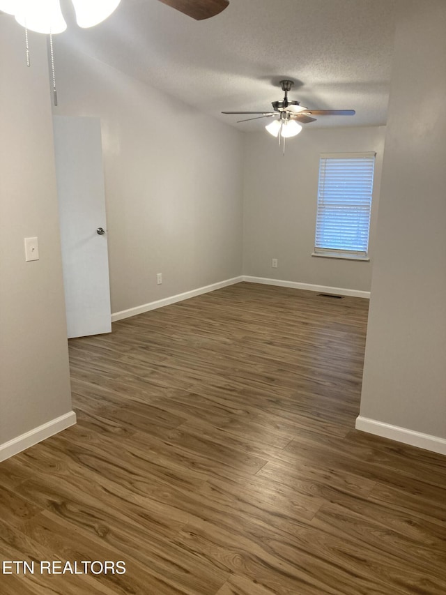 empty room featuring a textured ceiling, ceiling fan, and dark wood-type flooring