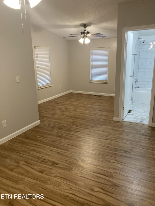 spare room featuring dark hardwood / wood-style floors, ceiling fan, and a textured ceiling