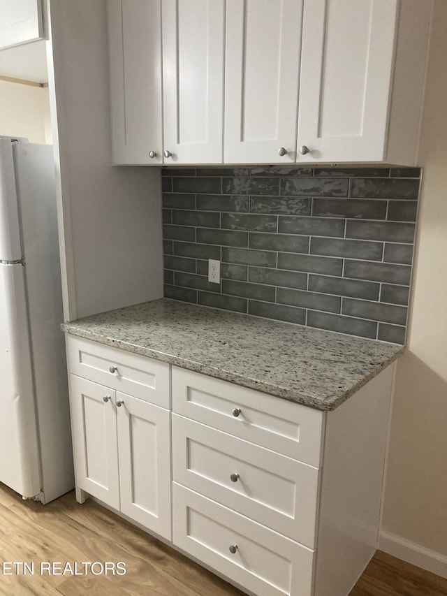 kitchen featuring stainless steel fridge, light hardwood / wood-style floors, white cabinetry, and tasteful backsplash