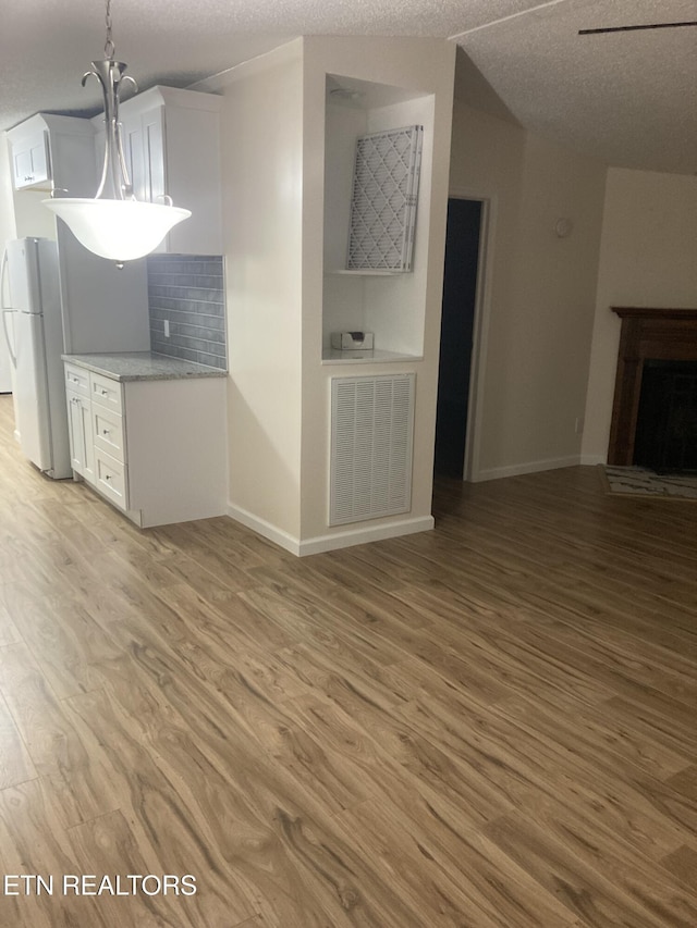 unfurnished living room with light hardwood / wood-style floors and a textured ceiling