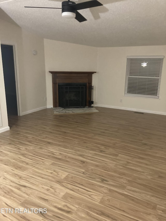 unfurnished living room with ceiling fan, wood-type flooring, and a textured ceiling