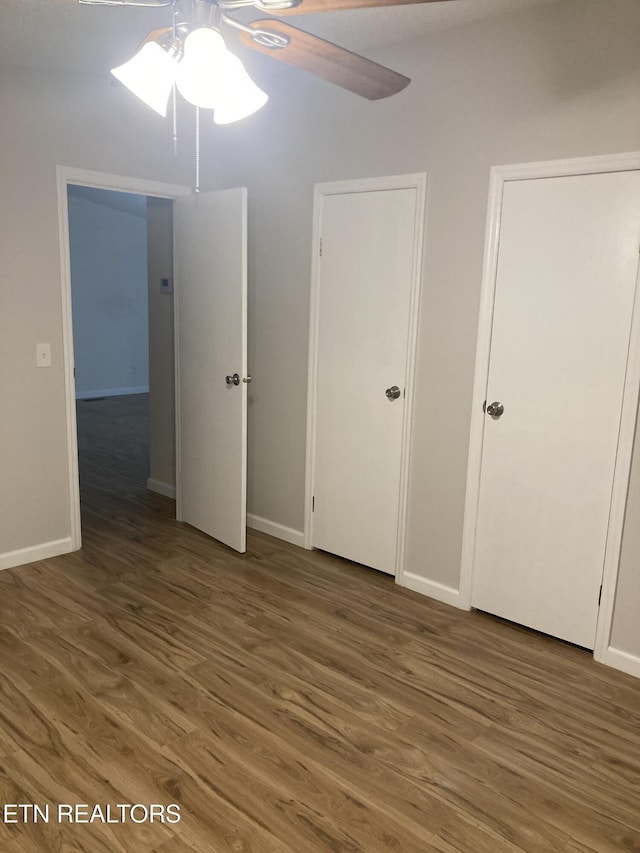 unfurnished bedroom featuring ceiling fan and dark hardwood / wood-style flooring