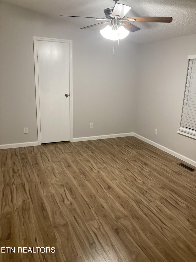 spare room featuring dark hardwood / wood-style flooring and a textured ceiling