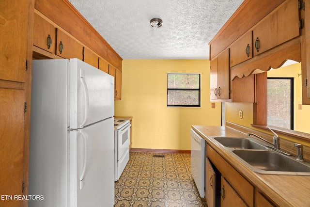 kitchen featuring a textured ceiling, white appliances, and sink