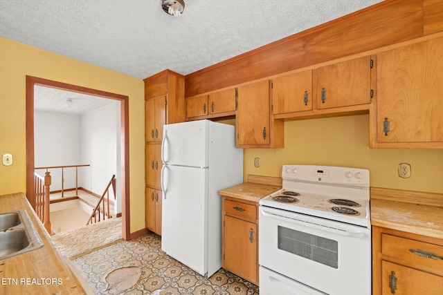 kitchen with a textured ceiling, white appliances, and sink