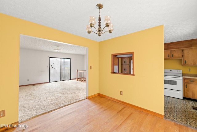 interior space featuring a notable chandelier, light wood-type flooring, and a textured ceiling