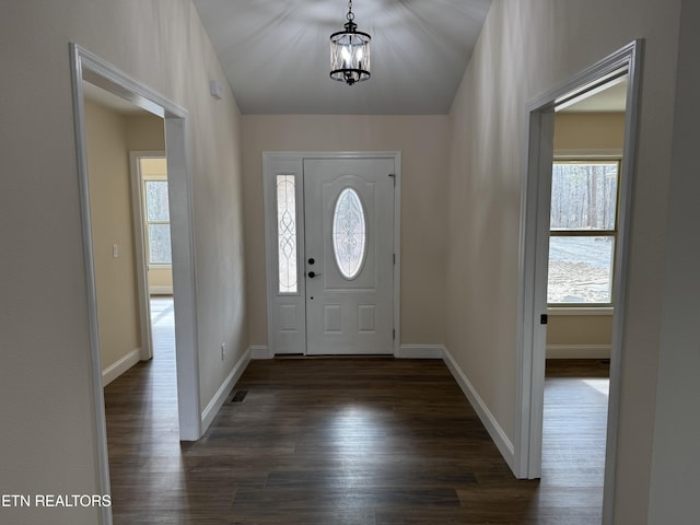 foyer entrance with dark wood-type flooring and a chandelier