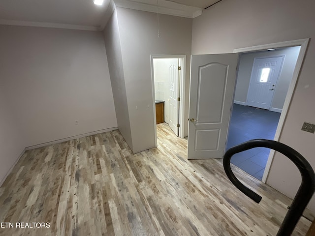 spare room featuring crown molding, a high ceiling, and light wood-type flooring