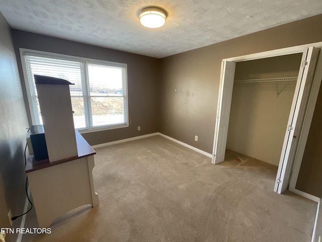 unfurnished bedroom featuring a textured ceiling, light carpet, and a closet