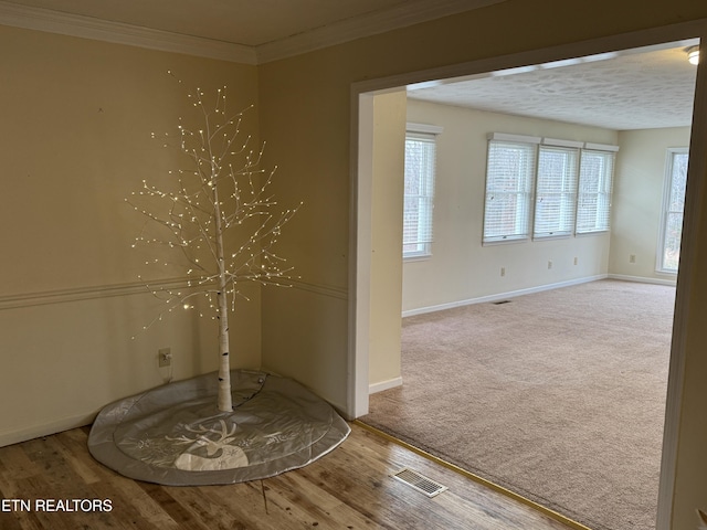 unfurnished room with a textured ceiling, wood-type flooring, and crown molding