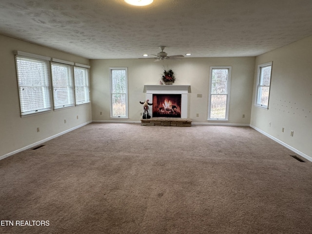 unfurnished living room with ceiling fan, carpet floors, and a textured ceiling