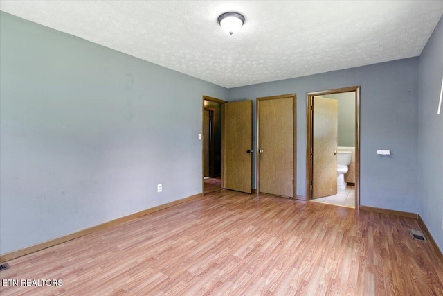 505 S S 38th St, Middlesboro, KY 40965 - unfurnished bedroom featuring light wood finished floors, a textured ceiling, a closet, and connected bathroom