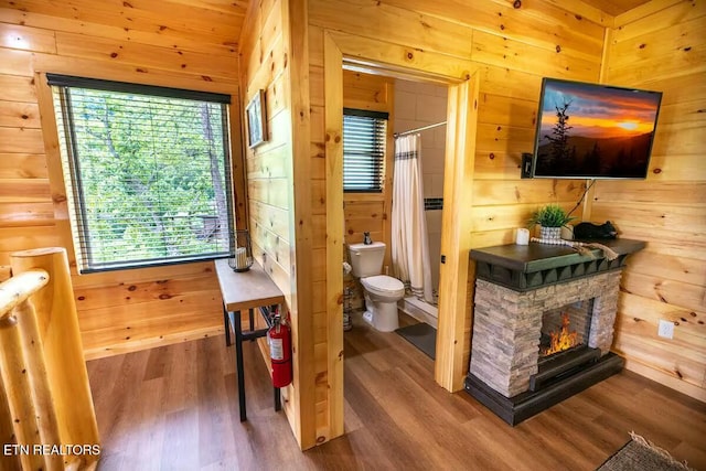 bathroom featuring hardwood / wood-style floors, wood walls, plenty of natural light, and toilet