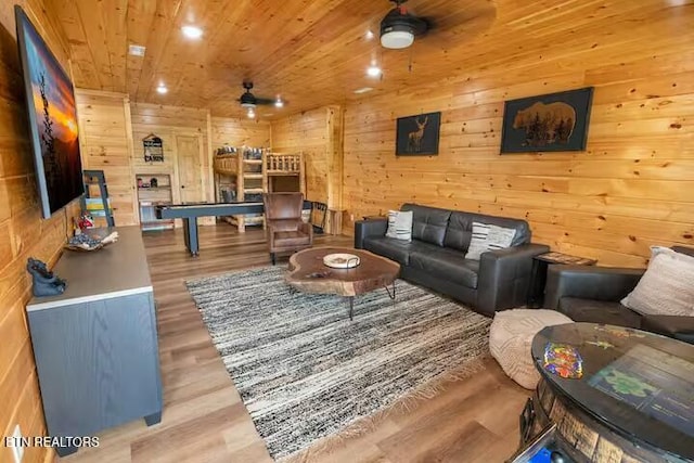 living room with wood walls, wood-type flooring, ceiling fan, and wood ceiling