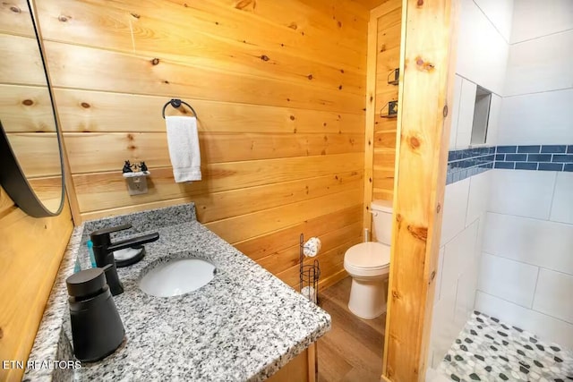 bathroom featuring toilet, wood walls, wood-type flooring, and sink