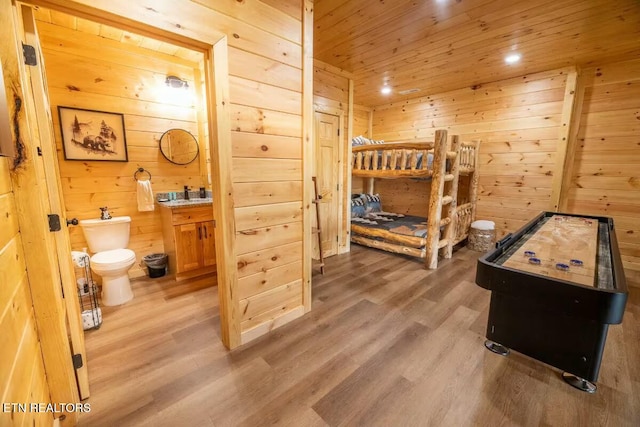 bedroom with ensuite bath, wooden ceiling, wood walls, and hardwood / wood-style flooring