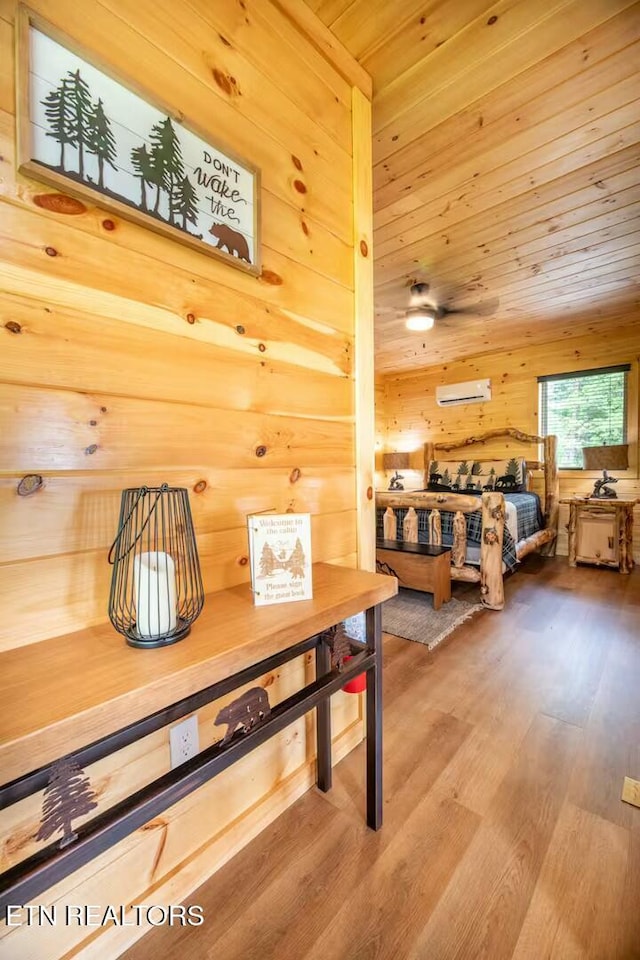 bedroom featuring wood walls, a wall unit AC, and hardwood / wood-style floors