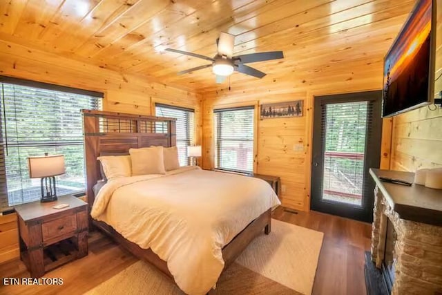 bedroom featuring wooden walls, wooden ceiling, wood-type flooring, ceiling fan, and access to exterior