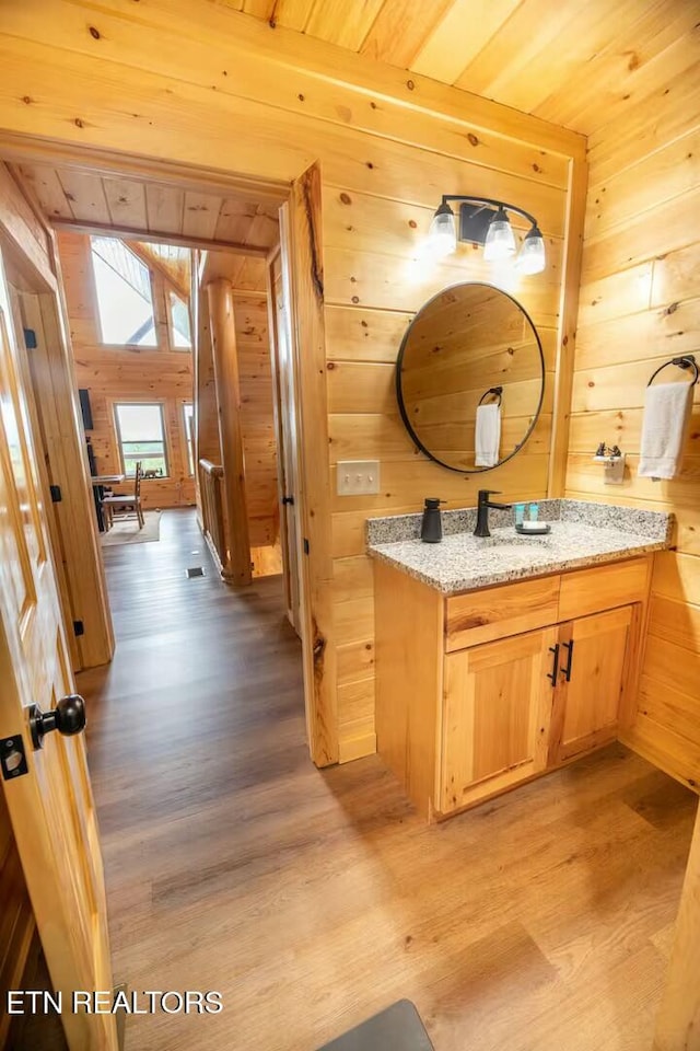 bathroom featuring wooden walls, wood-type flooring, and vanity