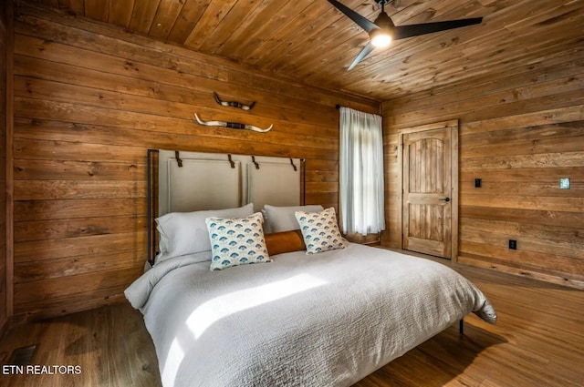 bedroom with ceiling fan, wood-type flooring, wood walls, and wooden ceiling