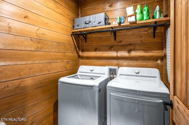 laundry room with wood walls and washing machine and clothes dryer