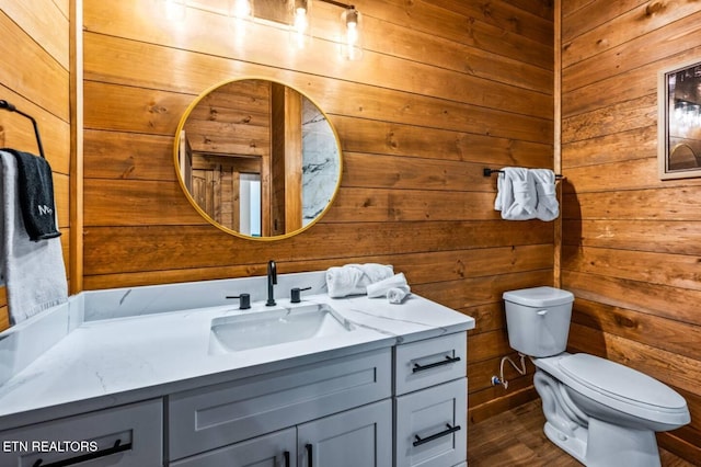 bathroom featuring wood-type flooring, vanity, toilet, and wooden walls