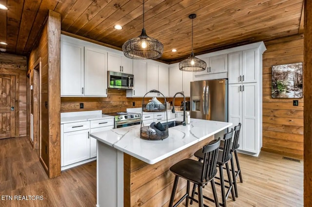 kitchen with a kitchen island with sink, white cabinets, and appliances with stainless steel finishes