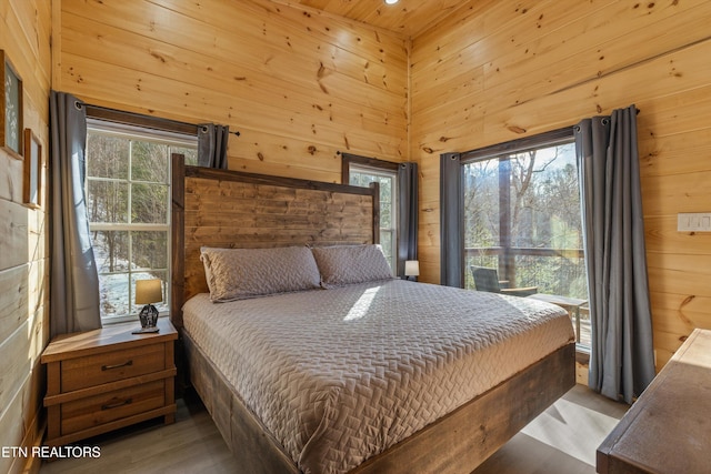 bedroom with a high ceiling, wood ceiling, and wooden walls