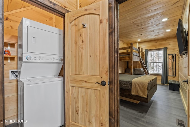 washroom with wooden ceiling, wood walls, hardwood / wood-style flooring, and stacked washer / dryer