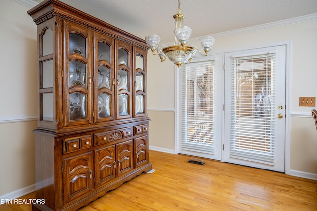 dining space featuring light hardwood / wood-style floors, ornamental molding, and an inviting chandelier