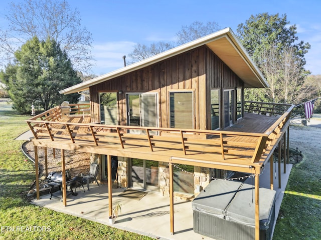 rear view of house with a lawn, a wooden deck, and a patio