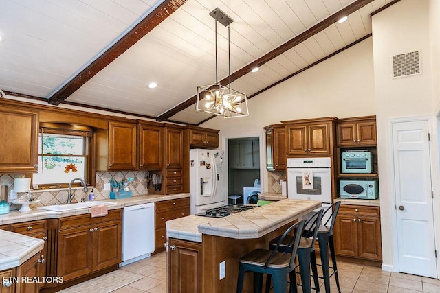 kitchen featuring sink, tile countertops, decorative light fixtures, white appliances, and a kitchen island