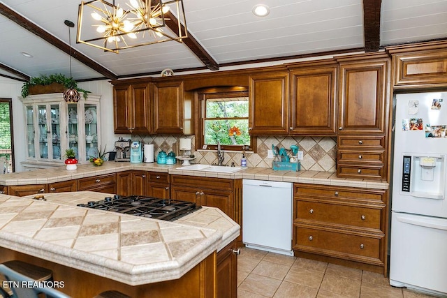 kitchen featuring tile counters, sink, an inviting chandelier, white appliances, and decorative backsplash