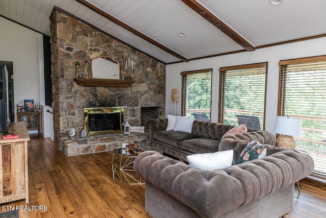 living room featuring lofted ceiling with beams, a stone fireplace, wood-type flooring, and a wealth of natural light