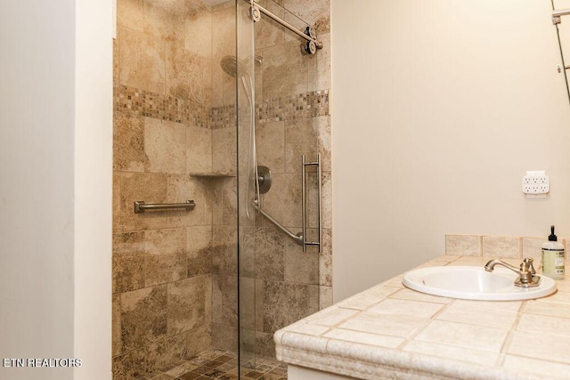 bathroom with tiled shower and sink