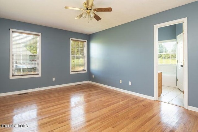 empty room with a wealth of natural light, ceiling fan, and light hardwood / wood-style floors