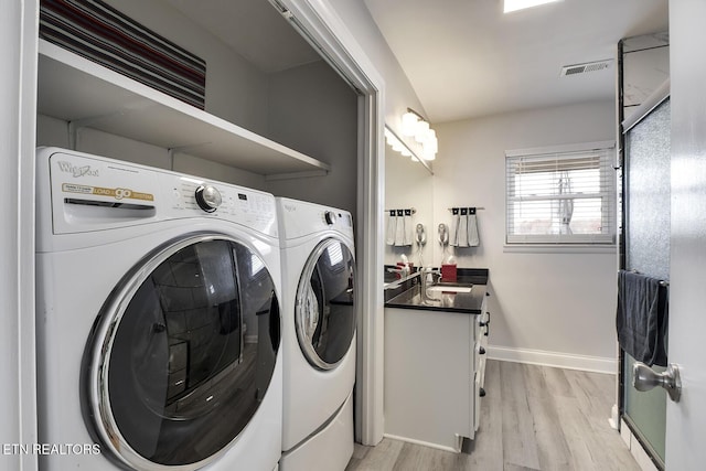 washroom with light hardwood / wood-style floors, separate washer and dryer, and sink