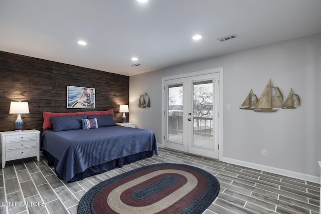 bedroom with dark hardwood / wood-style flooring, french doors, wooden walls, and access to exterior