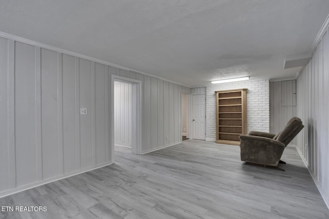 unfurnished room with a textured ceiling, ornamental molding, and light hardwood / wood-style flooring